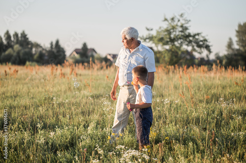 Fotografie Happy senior man Grandfather with cute little boy grandson playing in field