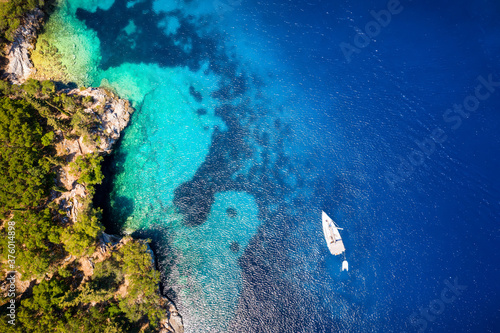 A sailboat moored off the coast of Kefalonia, Ionian Islands, Greece, with blue and turquoise sea and green hills