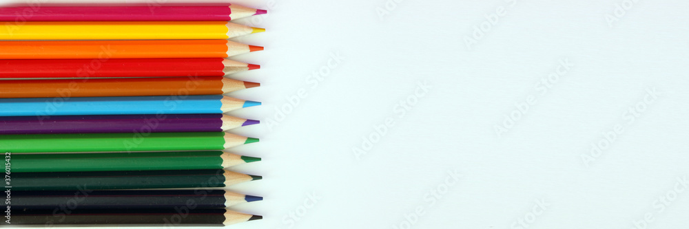 Colored pencils on a white background. Lots of different colored pencils. Colored pencil. Pencils are very sharp. Pencils lie on the left, evenly. Close-up. Copy space. Background. Flat lay. Banner Colored pencils on a white background. Lots of different colored pencils. Colored pencil. Pencils are very sharp. Pencils lie on the left, evenly. Close-up. Copy space. Background. Flat lay. Banner