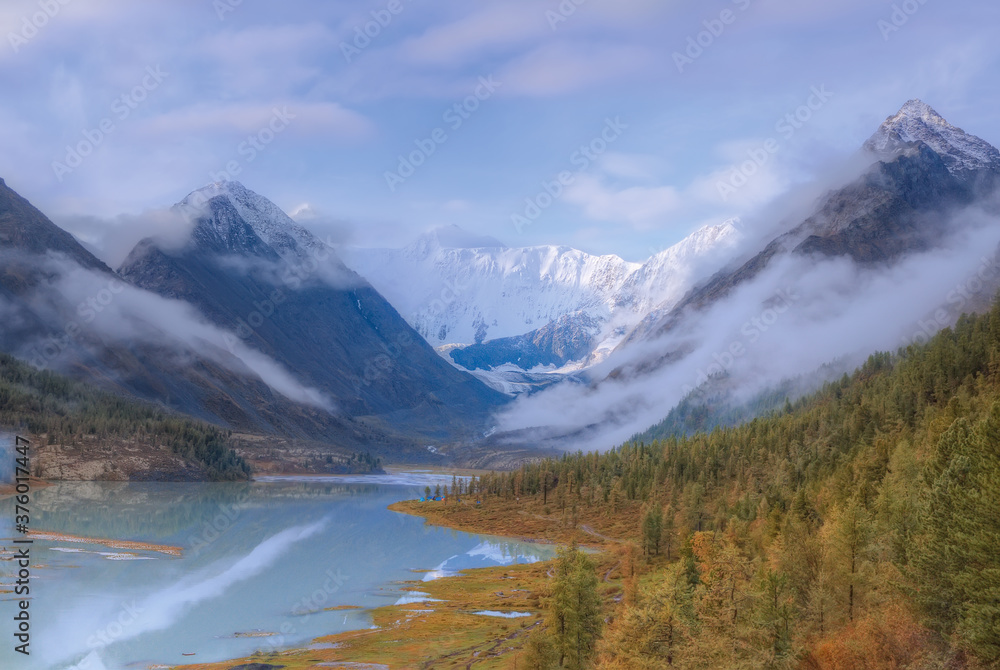 Natural background with the image of mountains in the fog. High white mountain. A beautiful lake. Morning fog. Soft focus. Selective focus on white mountain.