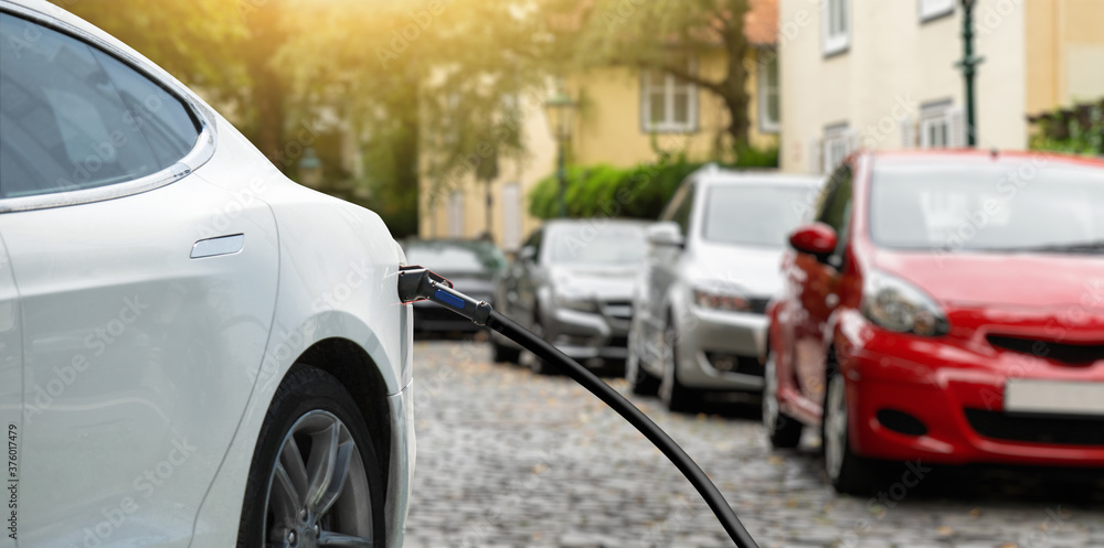Fototapeta premium Close-up of a charging electric car on the background of parked cars