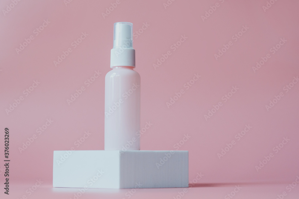 Pink plastic bottl container for cosmetics, on a white platform, on a pink background.