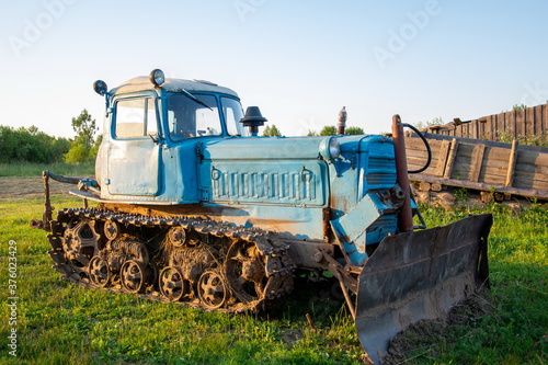 Rural farm field landscape. Soviet blue crawler bulldozer, front view photo