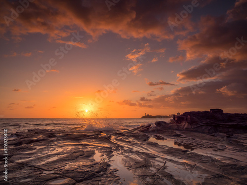 Golden Seaside Sunrise with Rockpool Reflections and Crashing Waves