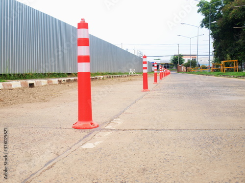 Traffic cones on concrete roads. On the left there is a metal seat wall, a row of orange cones for dividing traffic lanes. In driving the car on the road for safety. Focus close and choose the subject