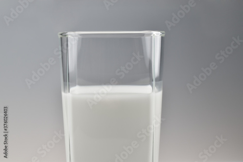 Glass of milk on grey gradient background, close-up photo