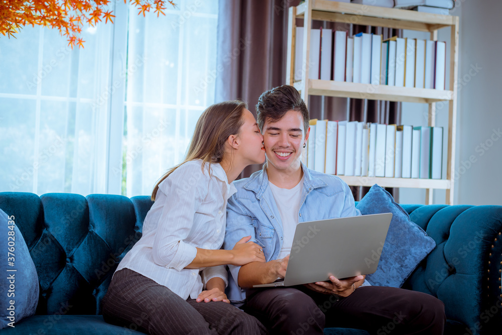 Portrait happy couple posing kiss to show congratulation when they see special thing on notebook at sofa in living room. Portrait happy couple posing kiss to show congratulation when they see special thing on notebook at sofa in living room.