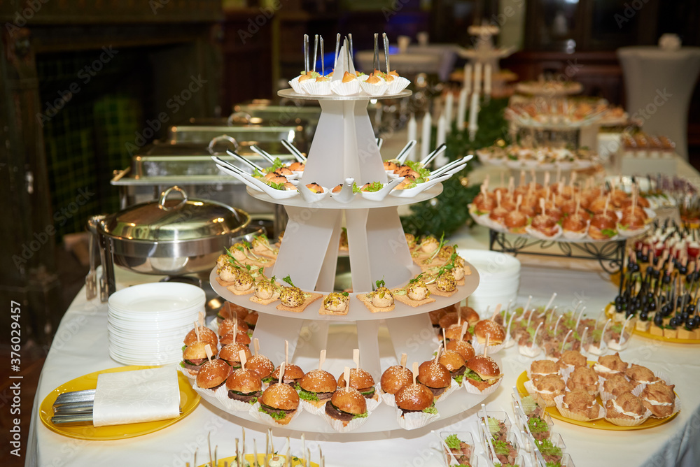 Buffet table with mini hamburgers, snacks, canape and appetizers at luxury wedding reception, copy space. Serving food and appetizers at restaurant. Catering banquet table