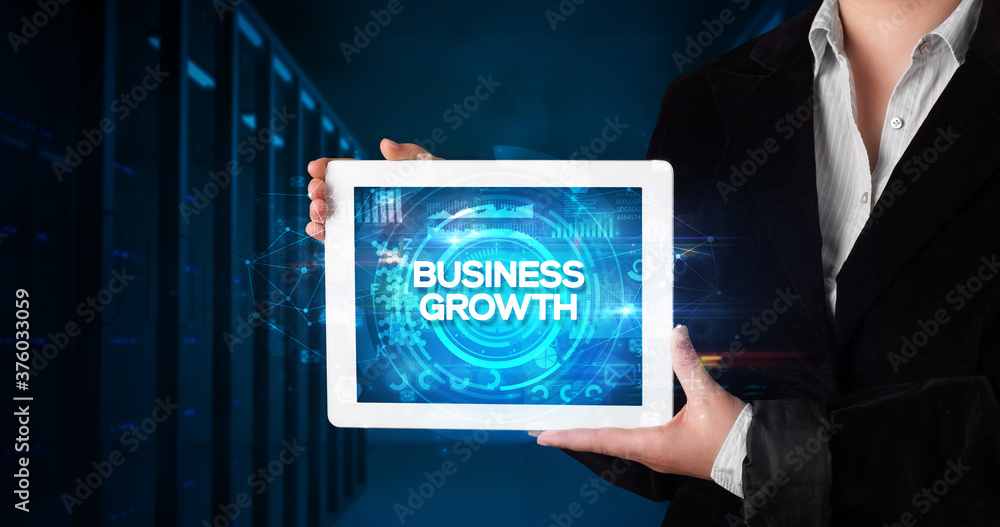 Young business person working on tablet and shows the inscription: BUSINESS GROWTH, business concept Young business person working on tablet and shows the inscription: BUSINESS GROWTH, business concept