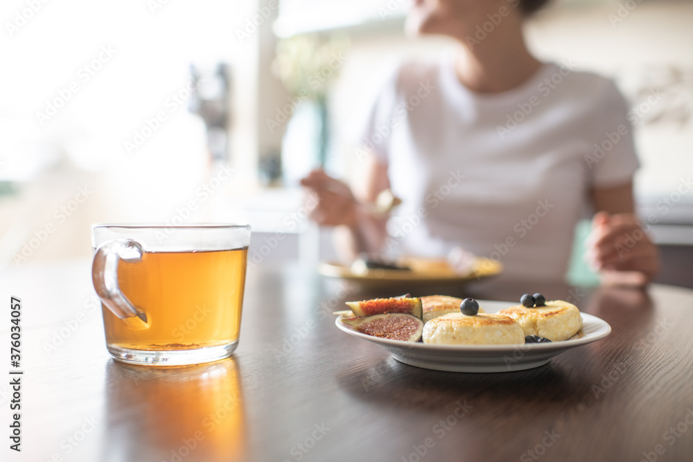 Having tasty breakfast with tea and cheese pancakes dessert (selective focus) Having tasty breakfast with tea and cheese pancakes dessert (selective focus)