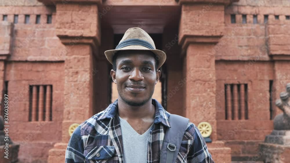Close-up portrait of young handsome African standing outdoors alone smiling looking at the camera Close-up portrait of young handsome African standing outdoors alone smiling looking at the camera
