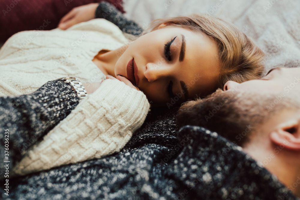 Couple in love lie in bed and cuddling. Affectionate young couple lying in bed together at the weekend. Close up.