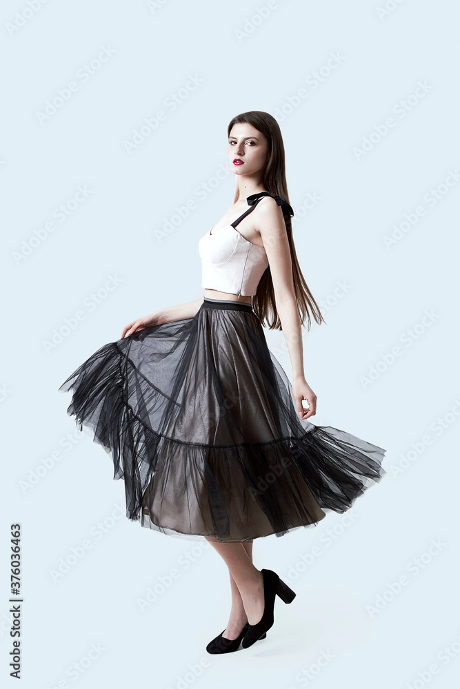 Young beautiful brunette girl in waving dark box pleated midi skirt posing in studio. Woman dancing or making a step. Young beautiful brunette girl in waving dark box pleated midi skirt posing in studio. Woman dancing or making a step.