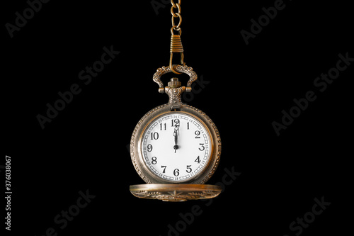 Retro bronze opened pocket watch on chain with white dial. Isolated on black background.