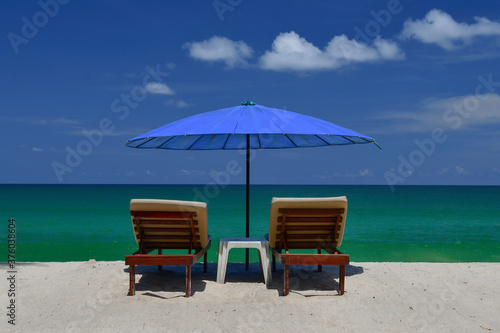 Topical beach, sunloungers and blue parasol