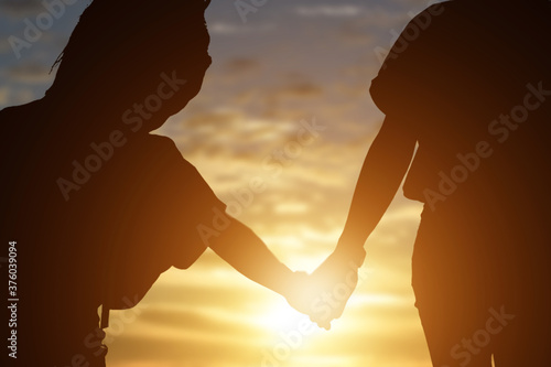 Two child holding hands a watching a beautiful sunset background.