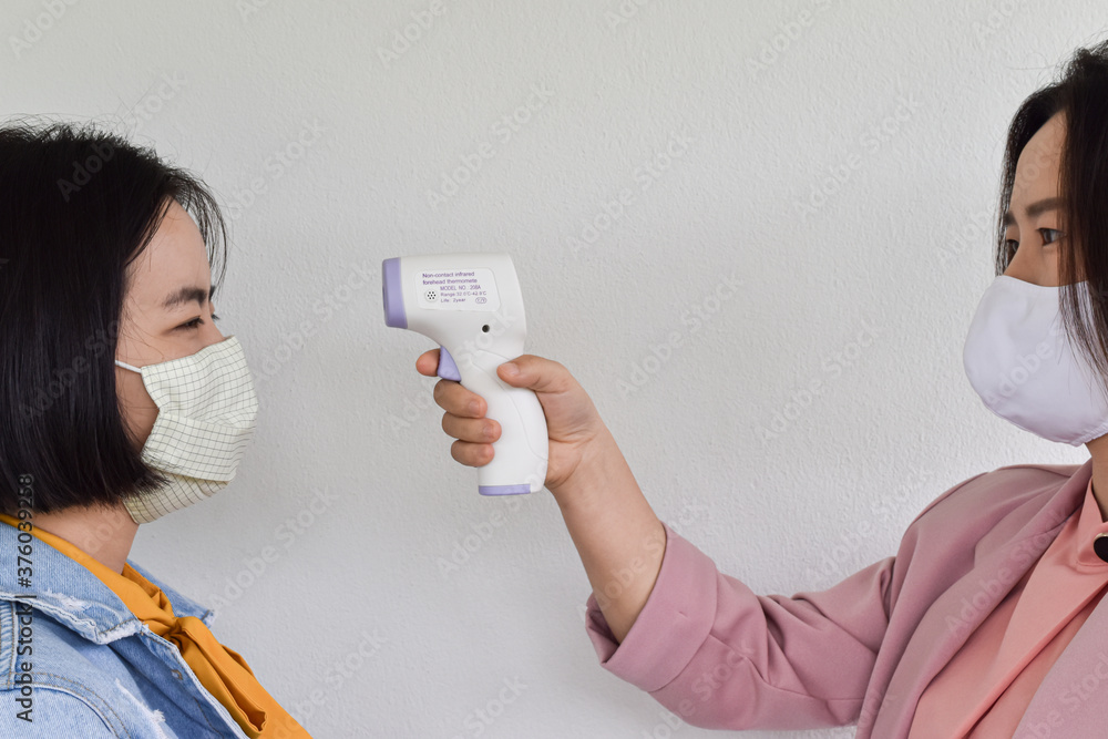 Women hand holding infrared forehead thermometer to check body temperature. Concept of protect from Coronavirus (COVID-19). Outbreak - Healthcare Women hand holding infrared forehead thermometer to check body temperature. Concept of protect from Coronavirus (COVID-19). Outbreak - Healthcare