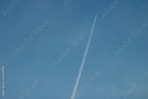 The white trail of a plane in the blue sky.