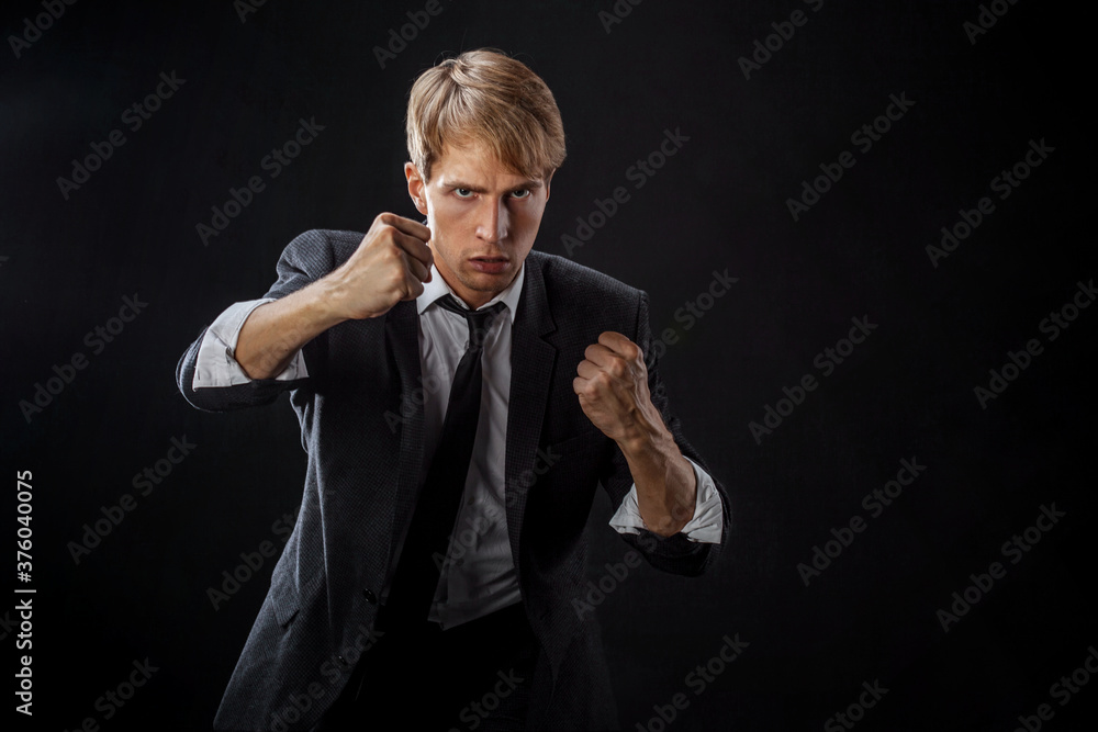 Competition in business, concept. A young man in a suit and tie fights with his fists,