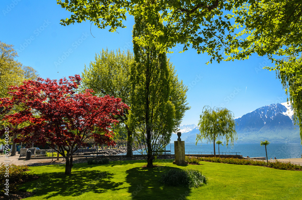 The park on the Vevey promenade with a view of the Geneva lake and the surrounding French Alps. Vevey, Switzerland.