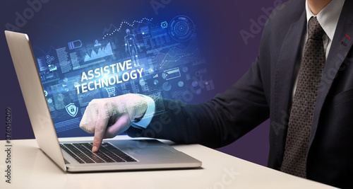 Businessman working on laptop with ASSISTIVE TECHNOLOGY inscription, cyber technology concept