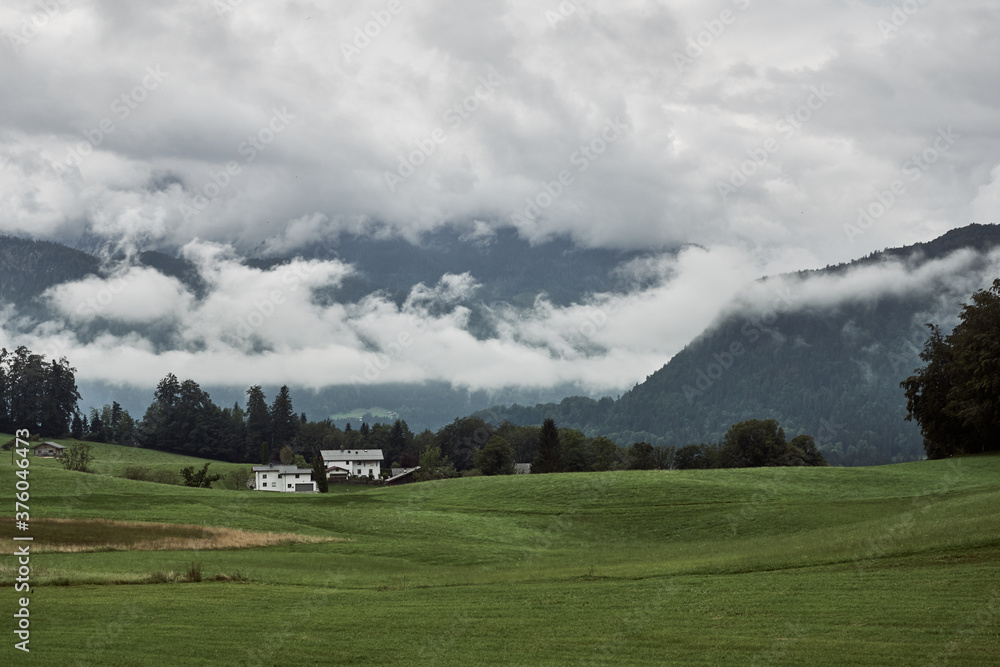 Storm clouds over green field and Berchtesgaden Alps near Bischofswiesen, Germany, Europe