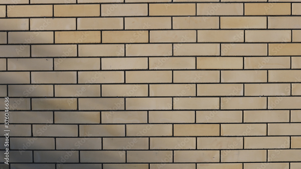 Fototapeta premium smooth brick wall of light sand color with contrasting dark seams as an empty basis for design ideas and advertising incarnations