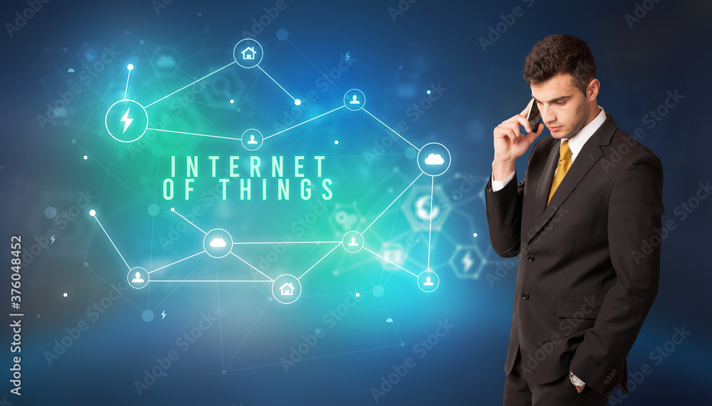 Businessman in front of cloud service icons with INTERNET OF THINGS inscription, modern technology concept Businessman in front of cloud service icons with INTERNET OF THINGS inscription, modern technology concept