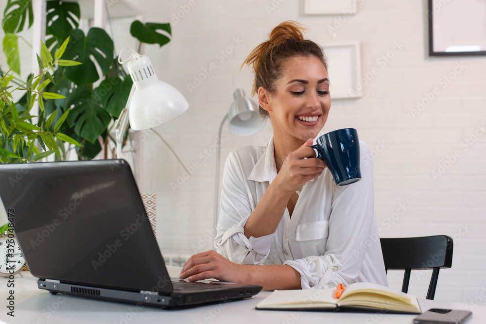 Woman drinking coffee in morning and using laptop for work Woman drinking coffee in morning and using laptop for work