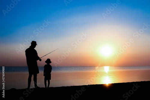 A Happy father and child fishermen catch fish by the sea on nature silhouette travel © Kostia