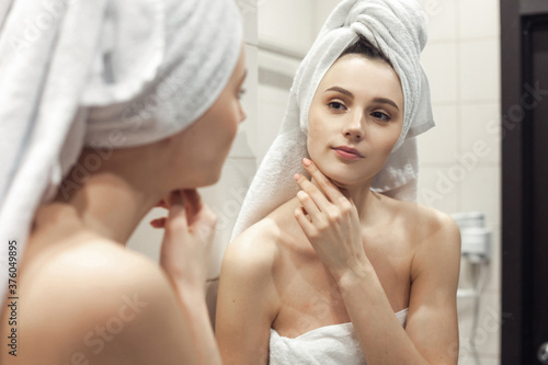 Young woman in bathroom behind mirror