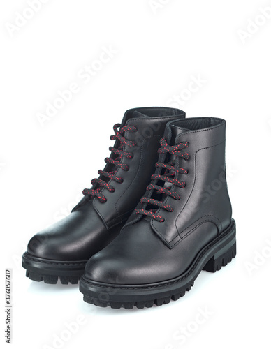 Black mountain boots made of durable leather, lace-up, with a massive sole, isolated on a white background with a shadow. The view from the top at an angle.