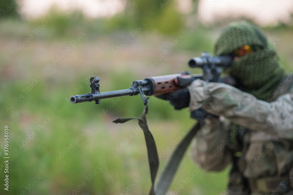 Sniper with rifle posing. Airsoft game