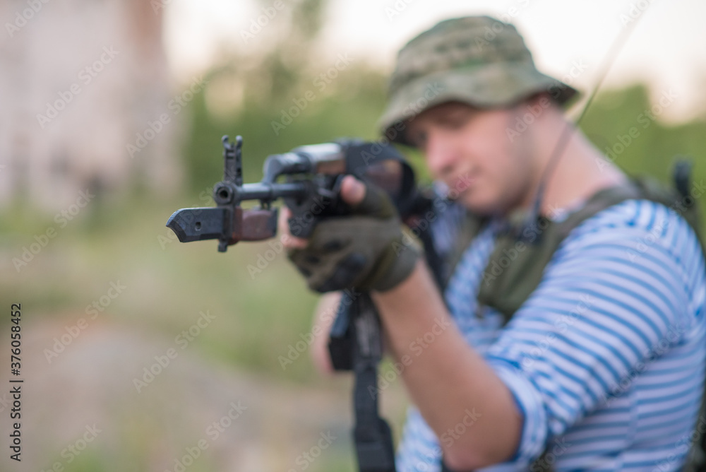 A professional airsoft player aims at his opponents A professional airsoft player aims at his opponents