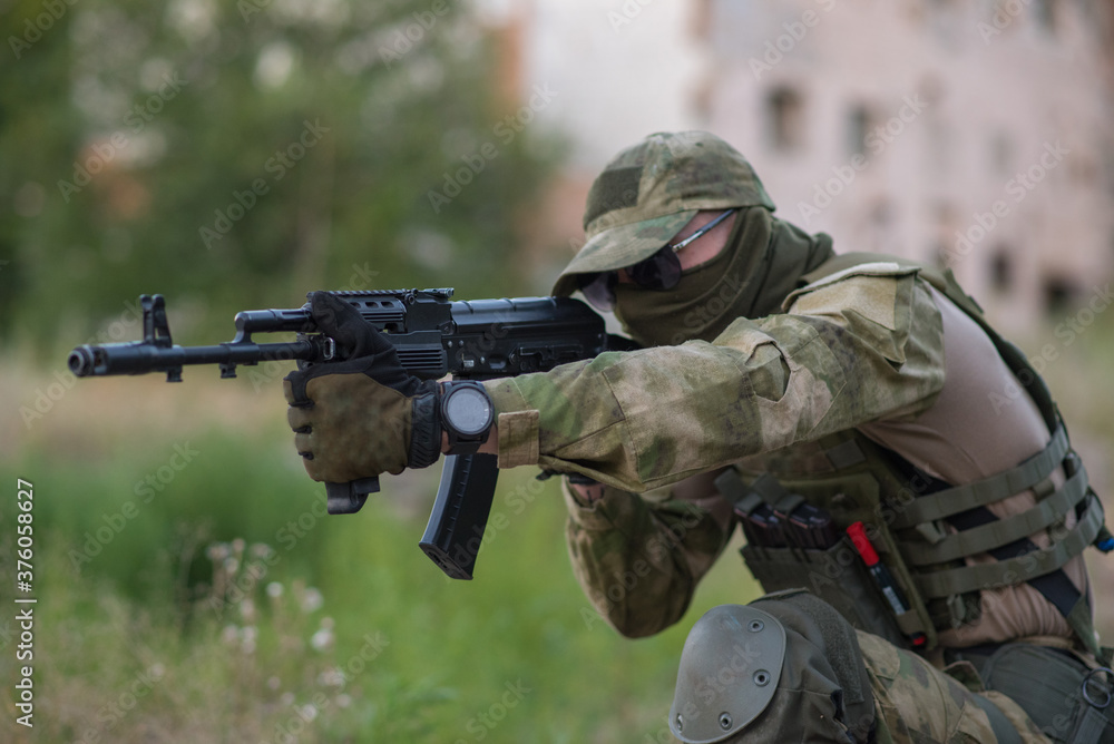 A professional airsoft player aims at his opponents A professional airsoft player aims at his opponents