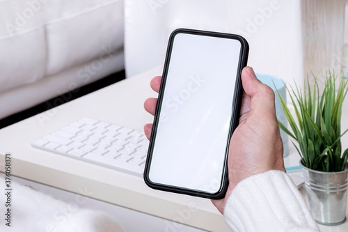Wallpaper Mural Cropped shot of man hand holding blank screen smartphone while sitting in living room at home. Torontodigital.ca