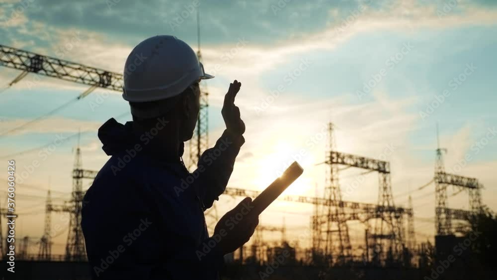 electrical silhouette worker engineer a working with digital tablet, near tower with electricity. energy business technology industry concept. electrical power studying reading documents on tablet electrical silhouette worker engineer a working with digital tablet, near tower with electricity. energy business technology industry concept. electrical power studying reading documents on tablet