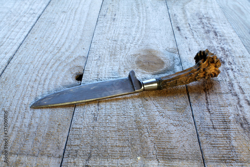 An old hunting knife lies on a table made of wooden boards