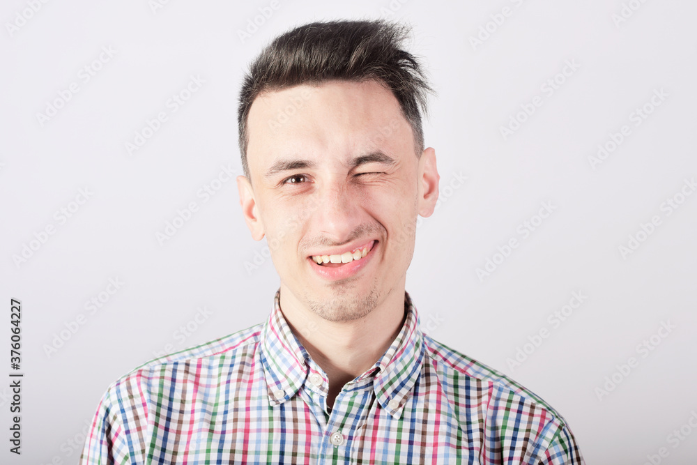 Guy student on a white background smiles and looks at the camera, winks Guy student on a white background smiles and looks at the camera, winks