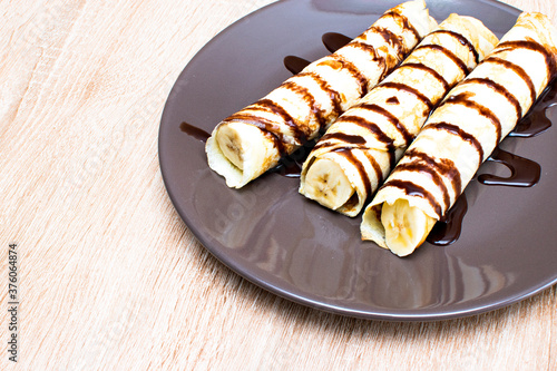Pancakes with banana and chocolate syrup on a plate. Breakfast with pancakes with banana and chocolate..