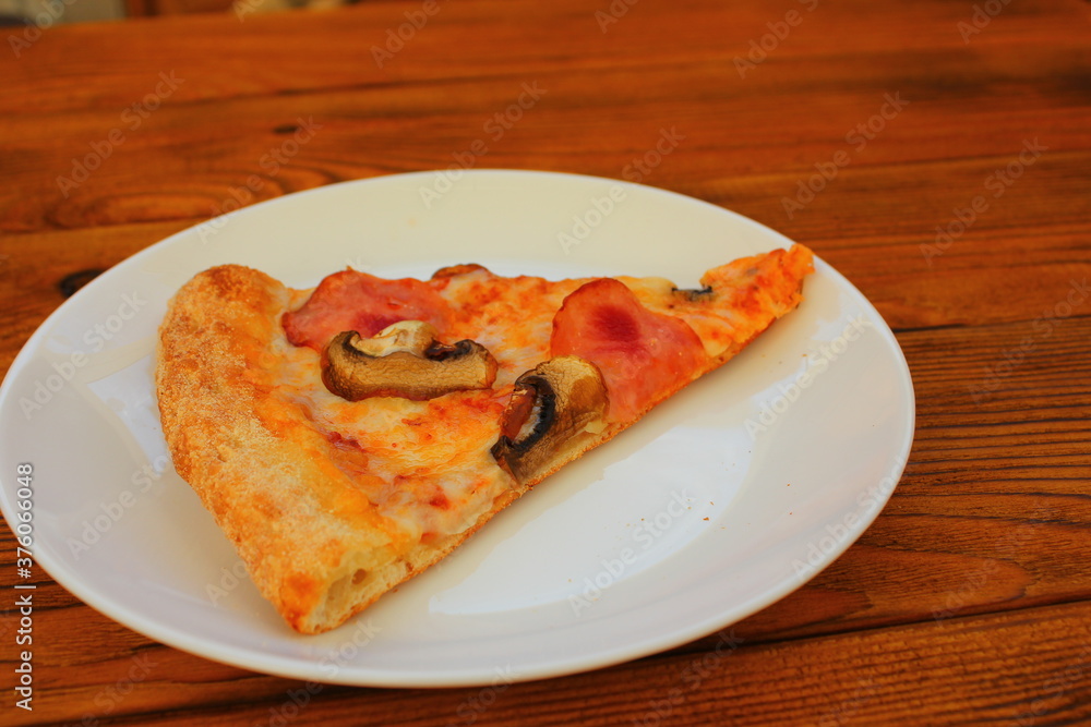 slice of pizza on a white plate on the table slice of pizza on a white plate on the table