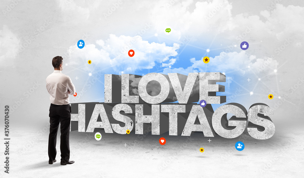 Young businessman standing in front of I LOVE HASHTAGS inscription, social media concept Young businessman standing in front of I LOVE HASHTAGS inscription, social media concept