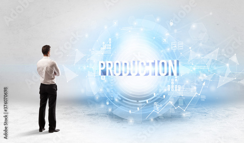 Rear view of a businessman standing in front of PRODUCTION inscription  modern technology concept
