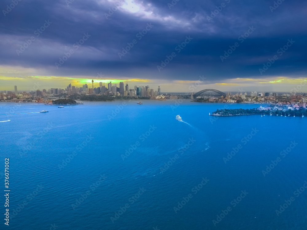 Panoramic drone aerial view over Sydney harbour on a cloudy sunset showing the nice colours of the CBD aparments and officer towers