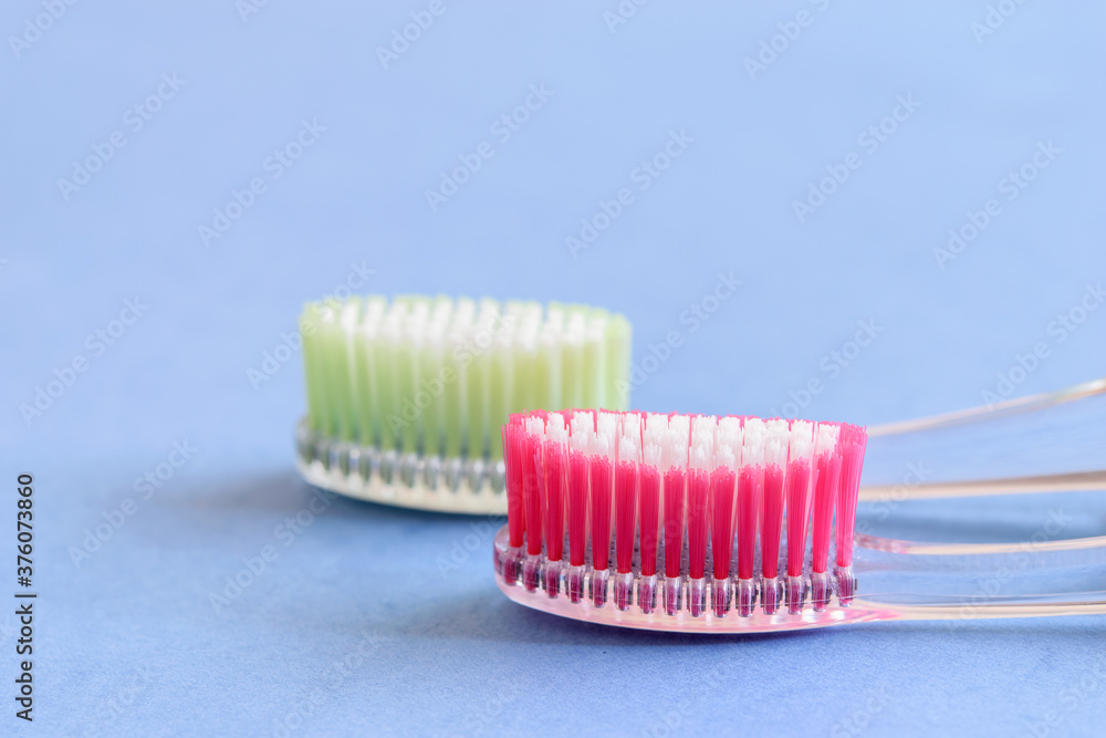 A couple of ecological plastic toothbrushes on the blue background close-up, isolated. A couple of ecological plastic toothbrushes on the blue background close-up, isolated.