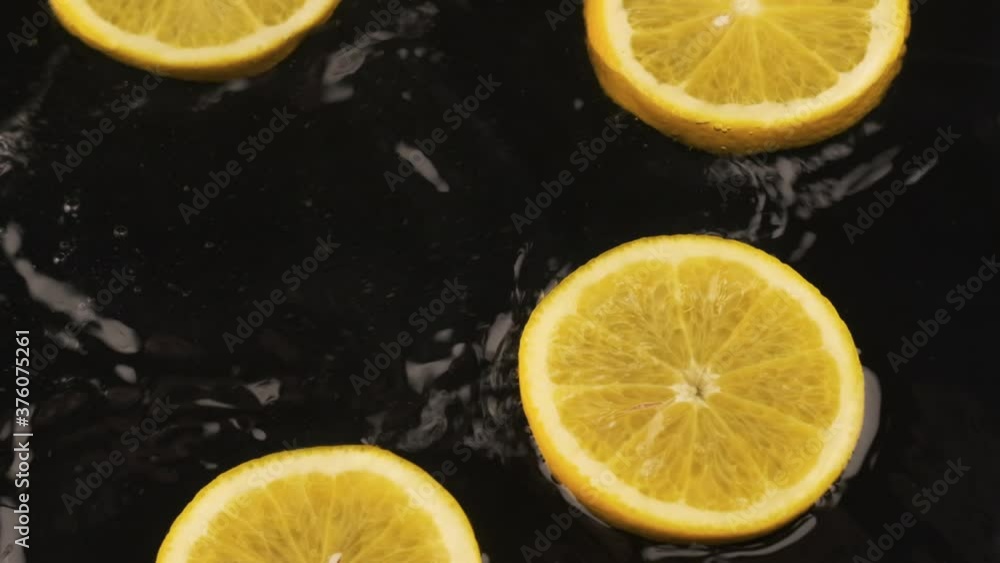 Falling orange slices into the water. Slow motion. Beautiful splash and drops of water Falling orange slices into the water. Slow motion. Beautiful splash and drops of water