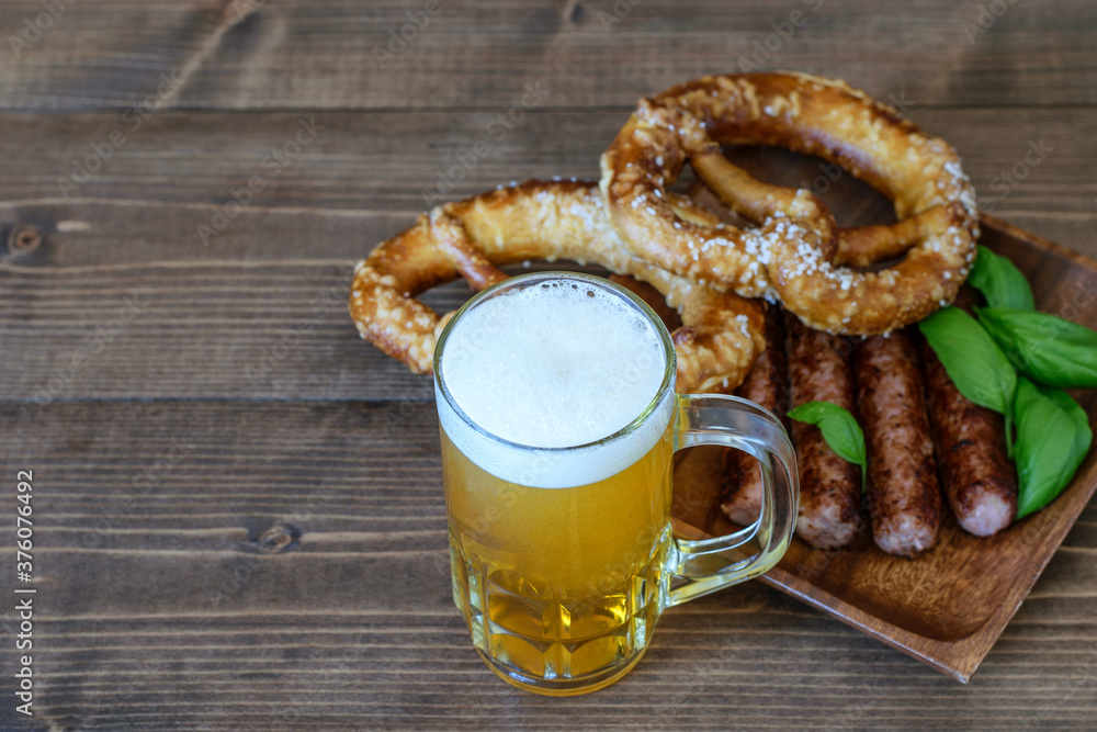 Mug of light beer, fresh pretzels and fried sausages for snack one day of October fest. Mug of light beer, fresh pretzels and fried sausages for snack one day of October fest.
