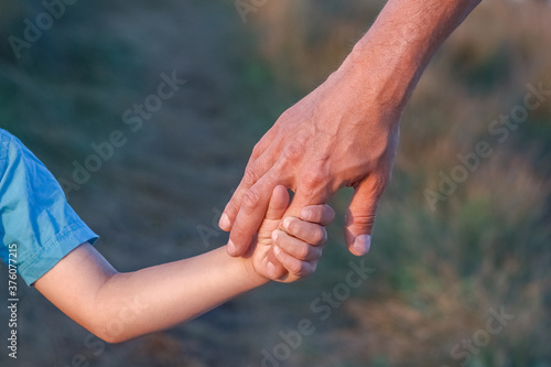 A Hands of a happy child and parent in nature in a park by the road © Kostia