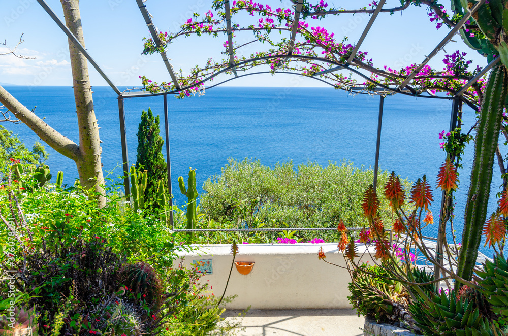 Amalfi Coast, Italy. The entrance to a garden with flowers and plants and with a enchanting view on the sea.