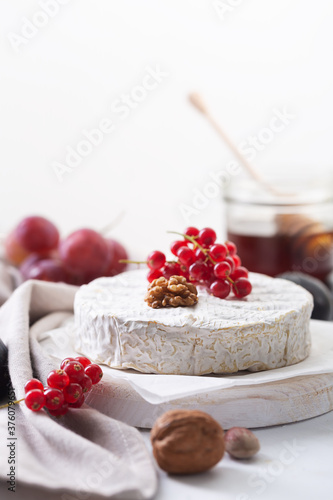 Camembert cheese with fruits, nuts and berries on a white background